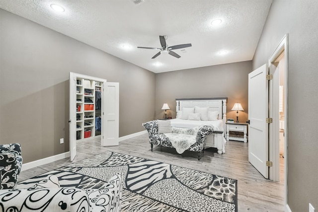 bedroom featuring ceiling fan, light hardwood / wood-style floors, and a textured ceiling