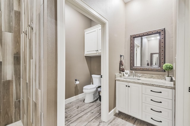 bathroom featuring walk in shower, hardwood / wood-style floors, vanity, and toilet