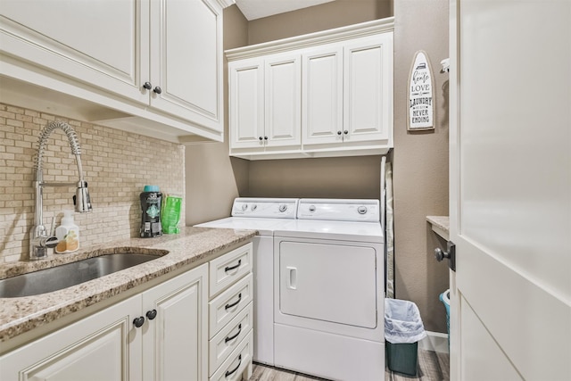 laundry room with washing machine and dryer, sink, cabinets, and light hardwood / wood-style floors