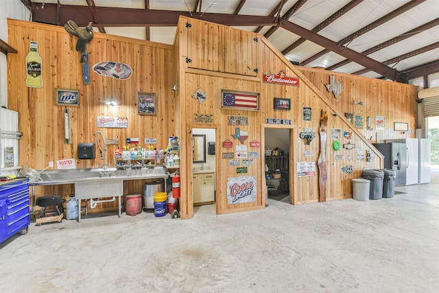 garage featuring wood walls and stainless steel refrigerator with ice dispenser