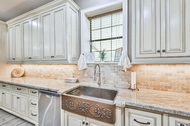 kitchen with dishwasher, light stone counters, decorative backsplash, and sink