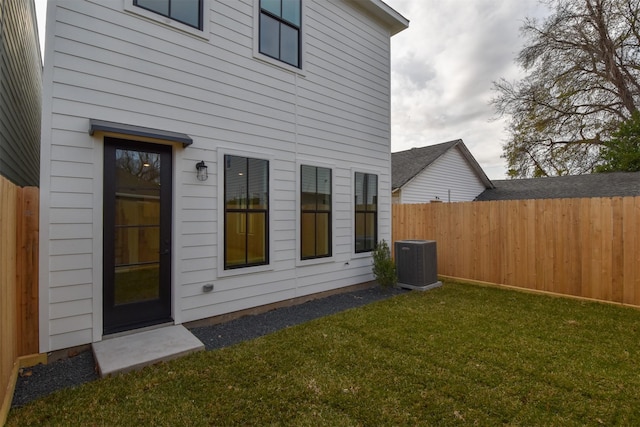 rear view of house featuring central air condition unit and a yard