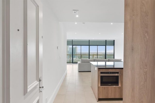 kitchen featuring light tile patterned floors, oven, and expansive windows