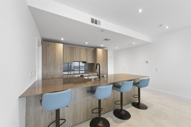 kitchen with kitchen peninsula, a breakfast bar area, and sink