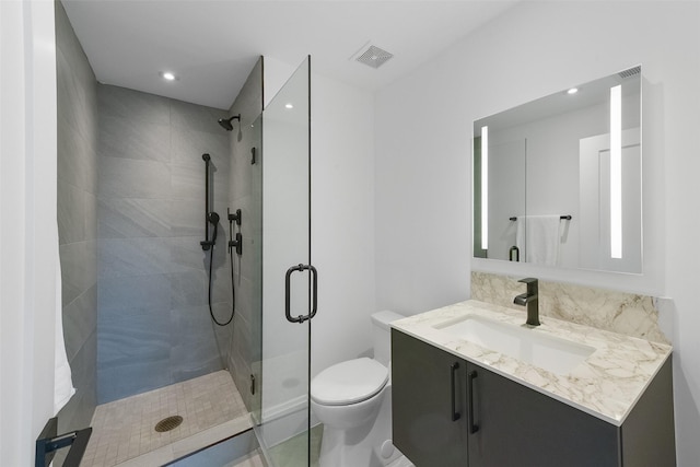 bathroom with vanity, a shower with shower door, and toilet