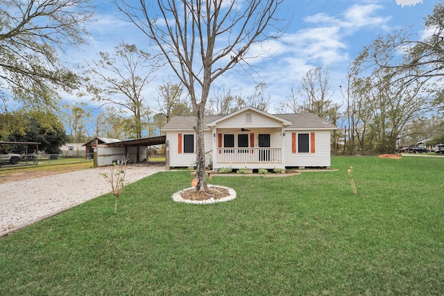 view of front of house featuring ceiling fan, a front lawn, covered porch, and a carport