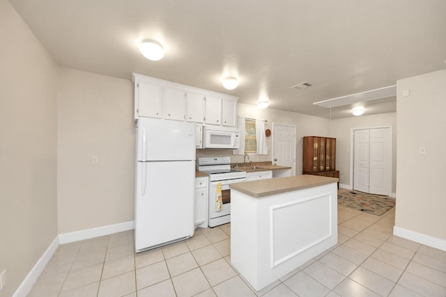 kitchen with light tile patterned flooring, white appliances, sink, and white cabinets