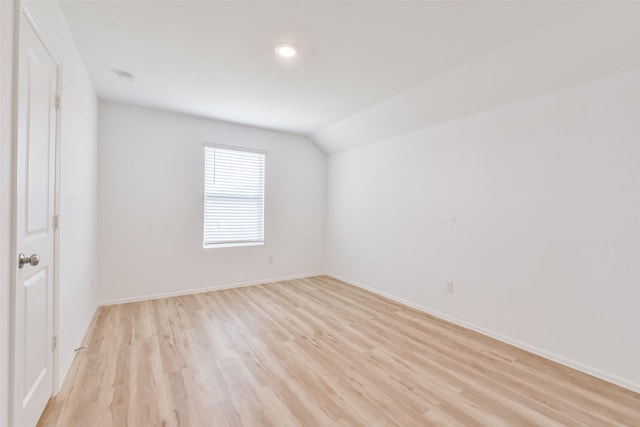 empty room with light hardwood / wood-style flooring and lofted ceiling