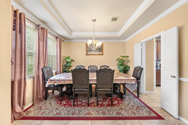 dining area featuring a tray ceiling, light tile patterned floors, ornamental molding, and an inviting chandelier