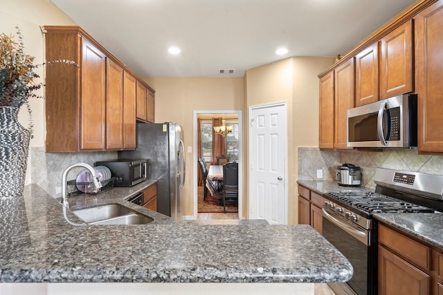 kitchen with an inviting chandelier, sink, dark stone countertops, appliances with stainless steel finishes, and tasteful backsplash