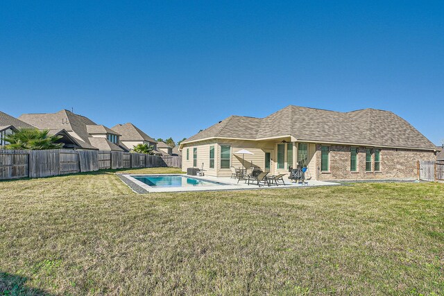 rear view of house featuring a fenced in pool, a patio area, and a yard