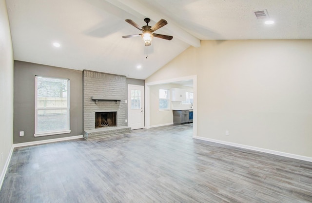 unfurnished living room with ceiling fan, a fireplace, hardwood / wood-style flooring, and lofted ceiling with beams