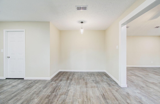 spare room featuring light hardwood / wood-style floors and a textured ceiling