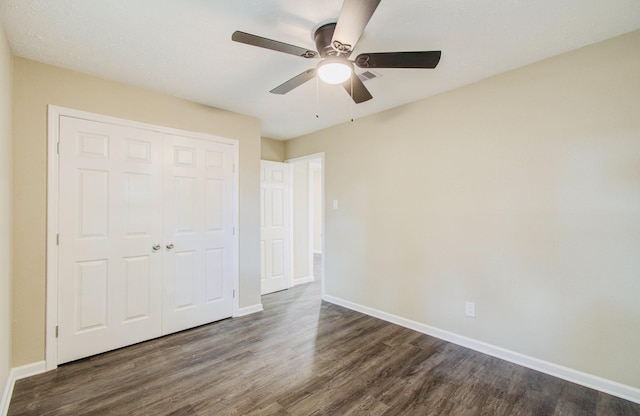 unfurnished bedroom featuring ceiling fan, a closet, and dark wood-type flooring