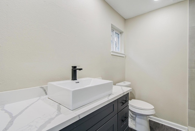 bathroom featuring wood-type flooring, toilet, and vanity