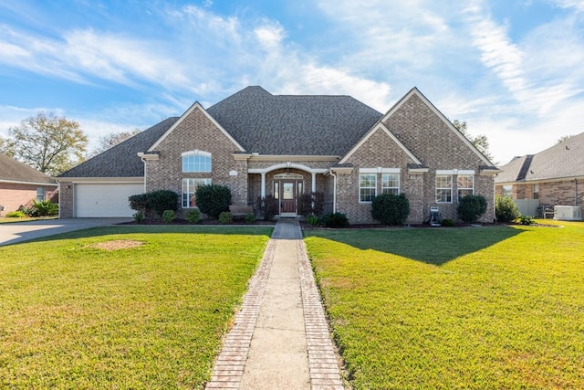 view of front of home featuring a garage, a front yard, and central AC