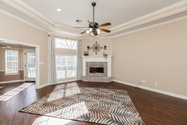 unfurnished living room featuring plenty of natural light, a raised ceiling, and ornamental molding