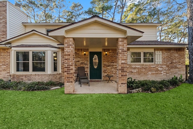 entrance to property with a lawn and a patio area