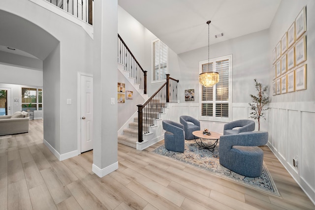 foyer with light wood-type flooring, a high ceiling, and an inviting chandelier