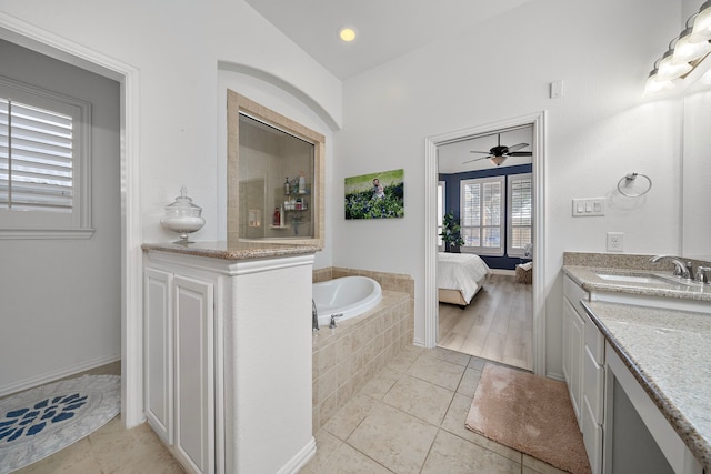 bathroom with tile patterned floors, ceiling fan, vanity, and a relaxing tiled tub