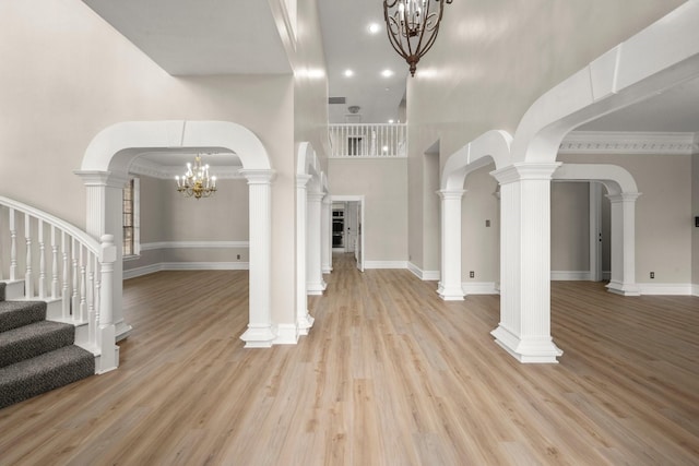 entryway with a notable chandelier, light wood-type flooring, and a high ceiling