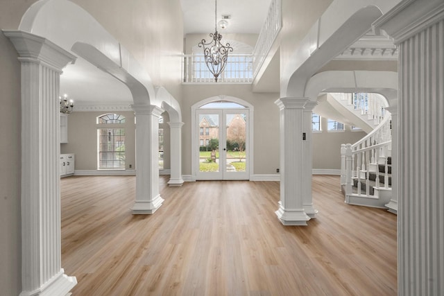 foyer entrance with light hardwood / wood-style floors, french doors, an inviting chandelier, and a towering ceiling