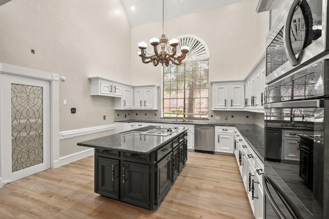 kitchen featuring a chandelier, stainless steel appliances, a towering ceiling, a kitchen island, and white cabinetry