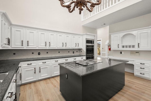 kitchen featuring dark stone countertops, stainless steel appliances, decorative backsplash, a kitchen island, and white cabinets