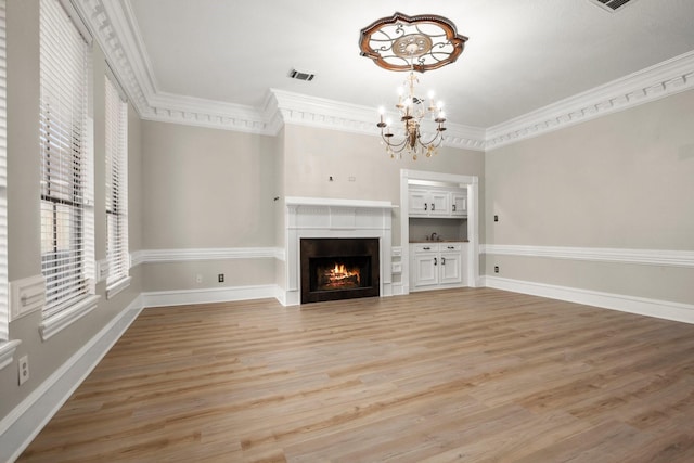 unfurnished living room featuring a chandelier, light wood-type flooring, and ornamental molding