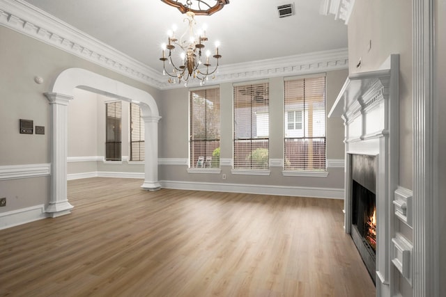 unfurnished living room featuring hardwood / wood-style floors, a premium fireplace, a chandelier, and crown molding