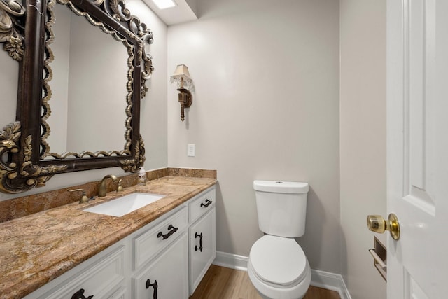 bathroom with toilet, vanity, and hardwood / wood-style flooring