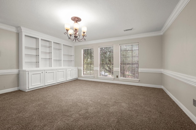 carpeted spare room with a textured ceiling, an inviting chandelier, built in features, and crown molding