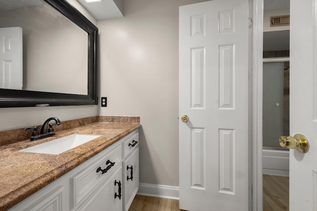 bathroom with shower / bath combination with glass door, wood-type flooring, and vanity