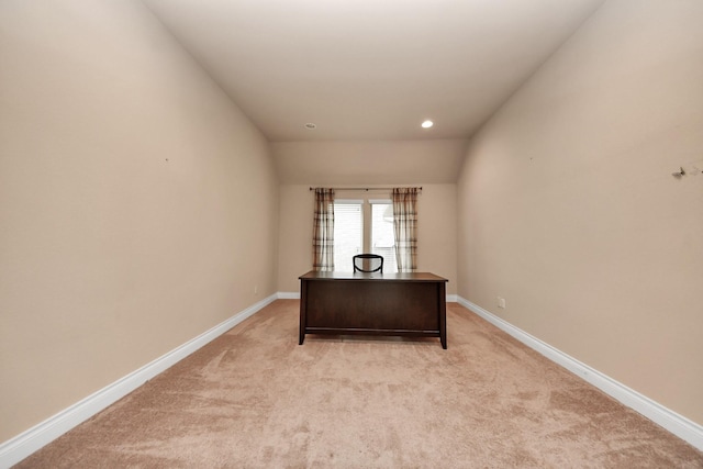 unfurnished office featuring light colored carpet and vaulted ceiling