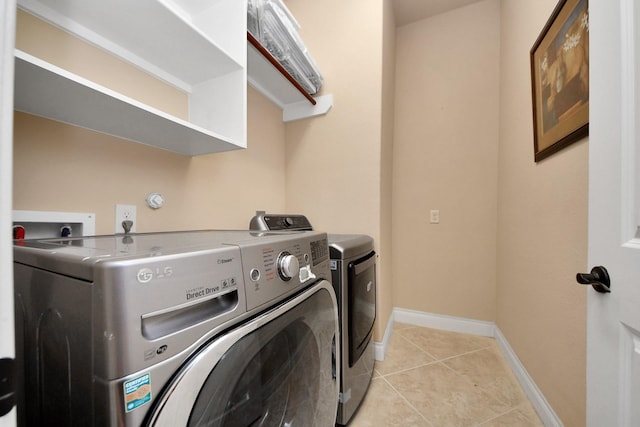 clothes washing area featuring light tile patterned flooring and washer and dryer