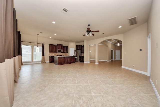 kitchen with appliances with stainless steel finishes, ceiling fan, light tile patterned floors, pendant lighting, and a center island