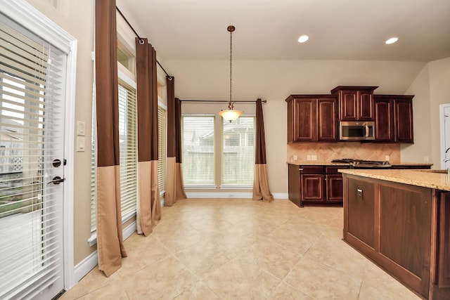 kitchen with light stone countertops, pendant lighting, tasteful backsplash, and light tile patterned floors