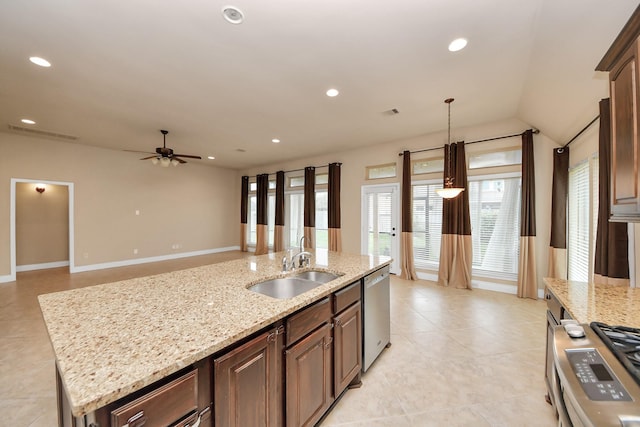 kitchen featuring light stone counters, stainless steel appliances, ceiling fan, a kitchen island with sink, and sink