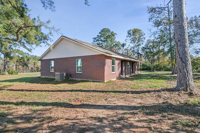 view of property exterior featuring central AC unit and a lawn