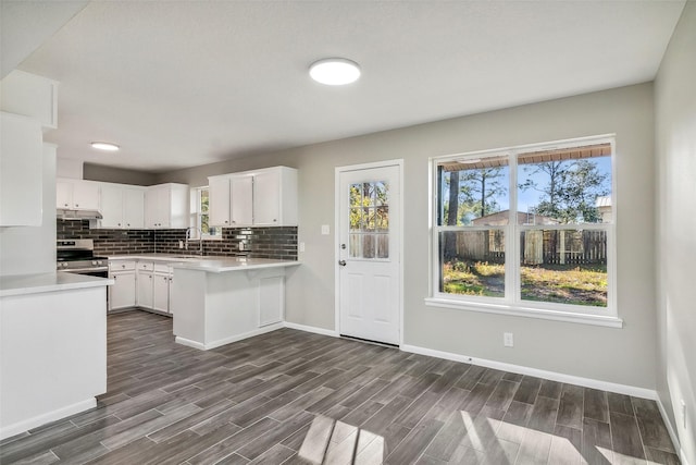 kitchen with backsplash, sink, kitchen peninsula, stainless steel range oven, and white cabinetry