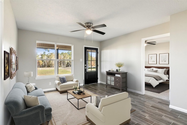 living room featuring a textured ceiling, dark hardwood / wood-style flooring, and ceiling fan