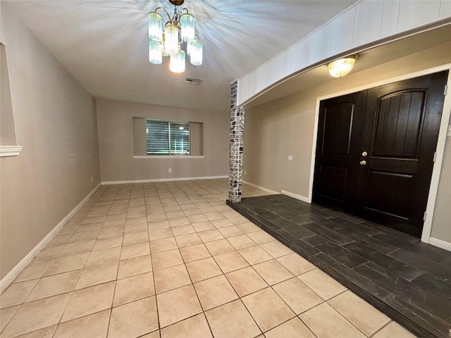 tiled foyer entrance with an inviting chandelier