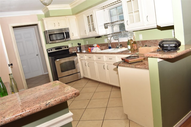 kitchen with appliances with stainless steel finishes, ornamental molding, sink, white cabinetry, and light tile patterned flooring