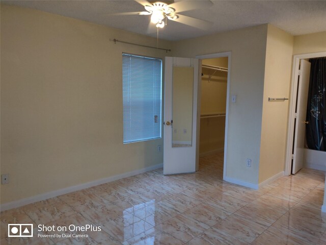 unfurnished bedroom with a walk in closet, ceiling fan, and a closet