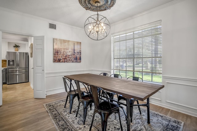 dining area with a chandelier, light hardwood / wood-style flooring, and ornamental molding