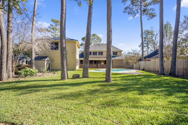 view of yard featuring a fenced in pool and a shed