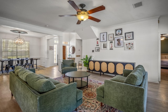 living room featuring hardwood / wood-style floors, ceiling fan with notable chandelier, and crown molding