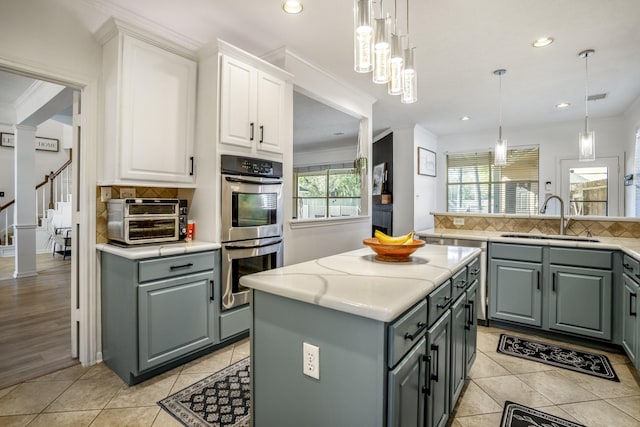 kitchen featuring pendant lighting, a center island, white cabinets, sink, and double oven