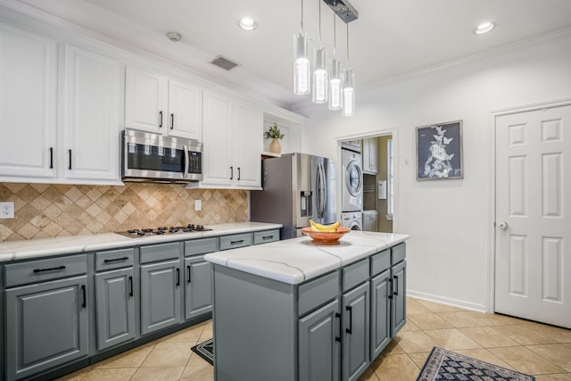 kitchen featuring a kitchen island, crown molding, stacked washer and dryer, and appliances with stainless steel finishes