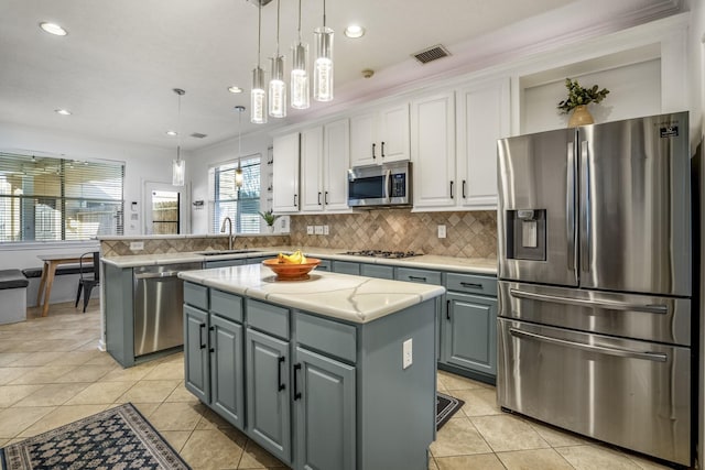 kitchen with a kitchen island, kitchen peninsula, decorative light fixtures, white cabinets, and appliances with stainless steel finishes